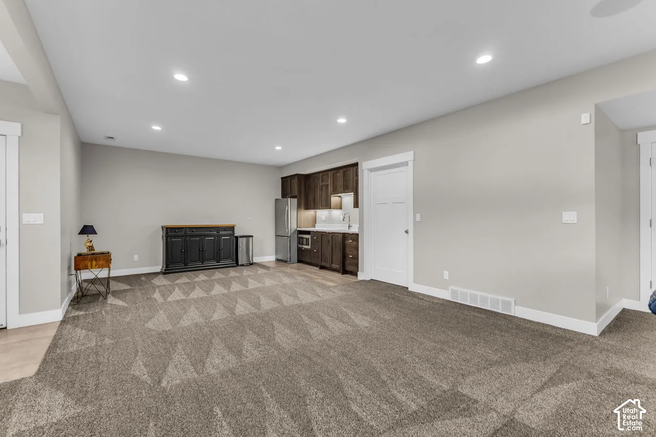 Kitchenette featuring dark wood cabinetry, stainless steel refrigerator, microwave, sink, and recessed lighting