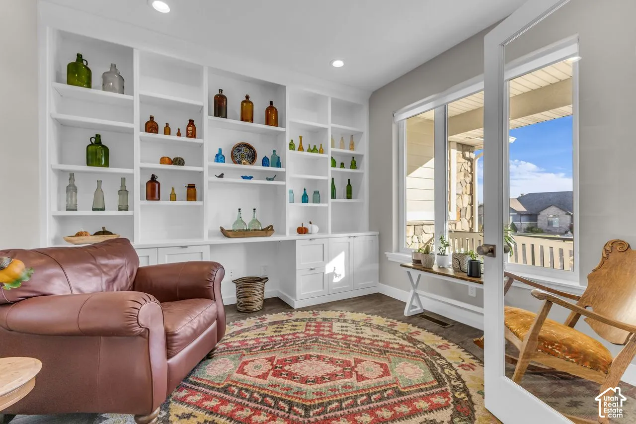 Built-in floor-to-ceiling shelving with cabinetry, recessed ceiling lighting, and wood-finish flooring