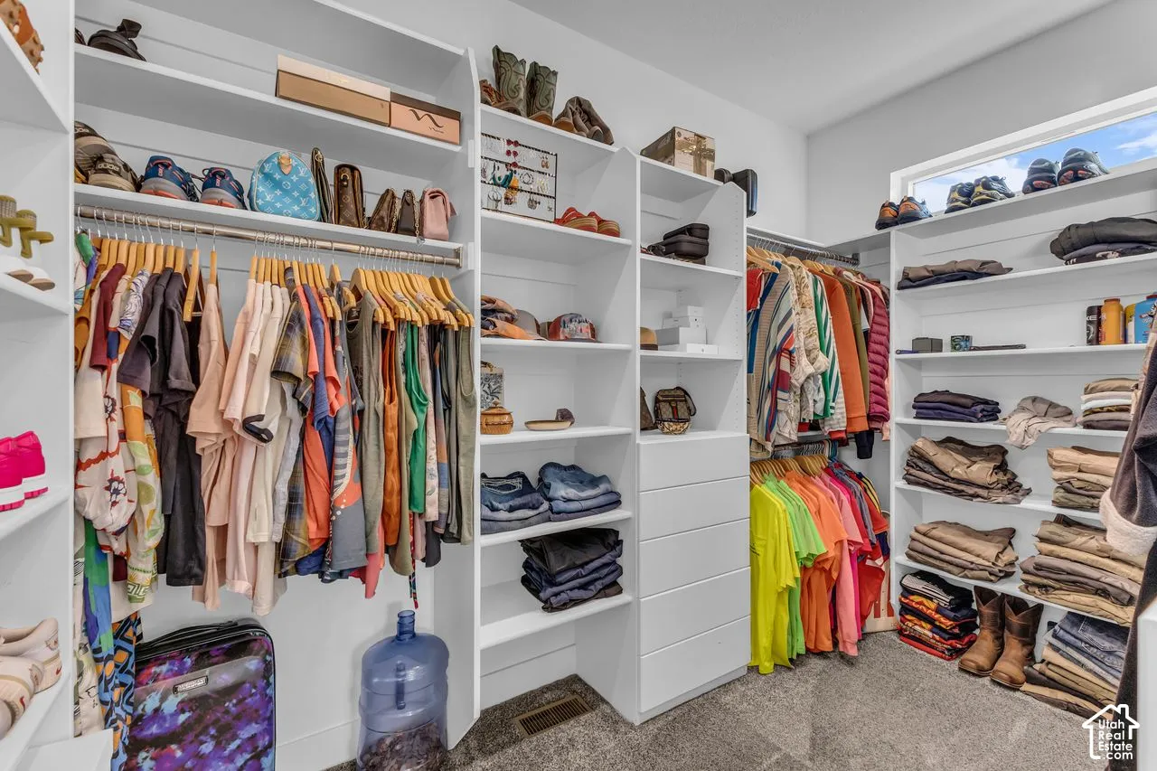 Walk-in closet featuring extensive built-in white shelving, integrated hanging rods, a column of five drawers, and a horizontal transom window