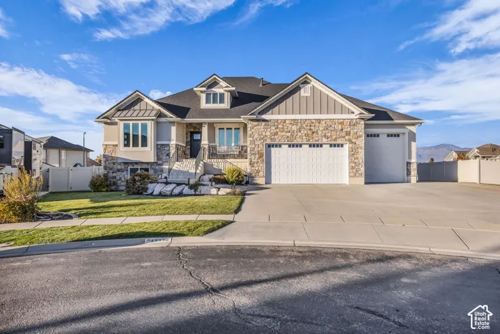Multi-level exterior featuring stone veneer siding, vertical board-and-batten accents, a three-car garage, and a concrete driveway