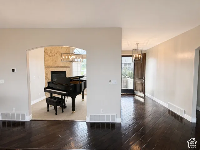 Arched entryway featuring a floor-to-ceiling stone-clad fireplace, dark wood-finish flooring, and geometric pendant lighting