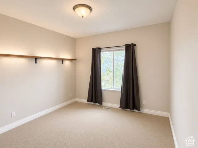 Room featuring neutral carpeting, a dual-pane sliding window, and a built-in wall-mounted shelf with integrated lighting