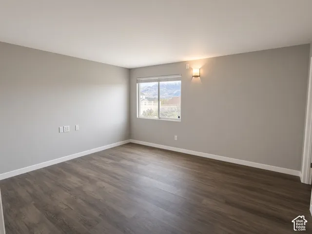 Neutral-toned walls, wood-finish flooring, a wall-mounted light fixture, and a window with mountain scenery