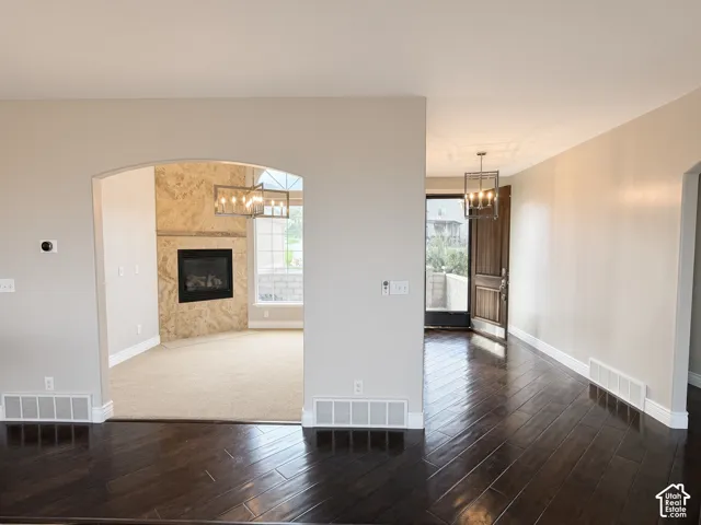 Interior featuring an arched entryway, floor-to-ceiling stone-surround fireplace, wood-finish flooring, and industrial-style pendant lighting