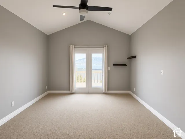 Vaulted ceiling room featuring neutral carpeting, a central ceiling fan, built-in wall shelving, and glass-paneled double doors