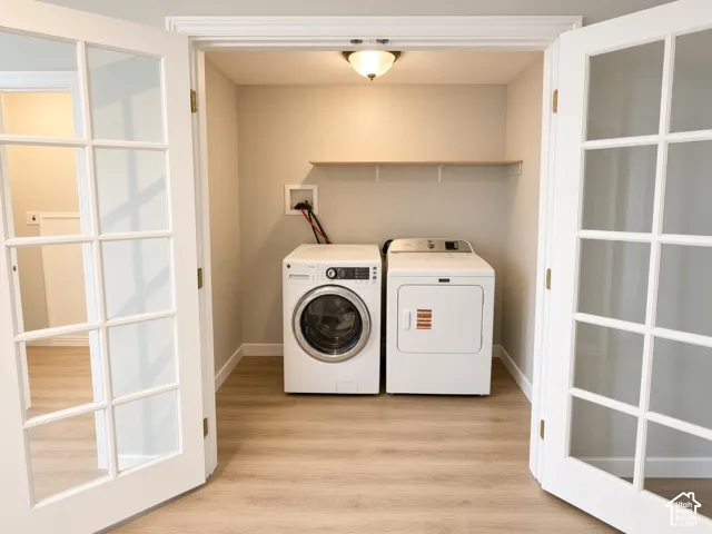 Laundry space featuring wood-finish flooring, white French doors, and a built-in wall shelf