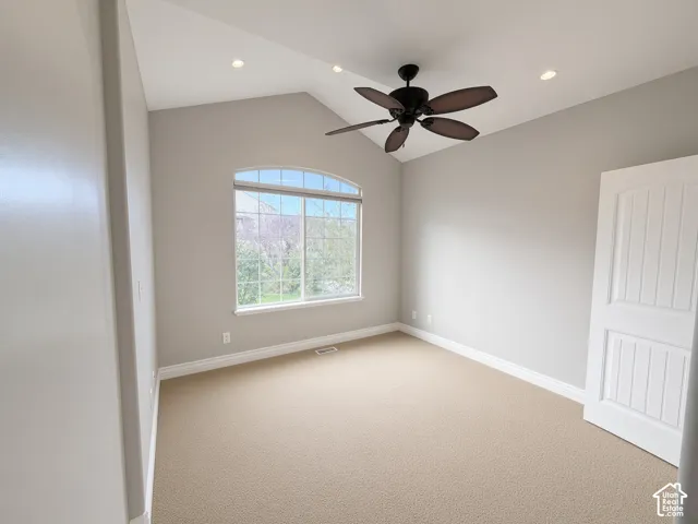 Vaulted ceiling with recessed lighting, arched window, carpeted flooring, and a ceiling fan with integrated lighting