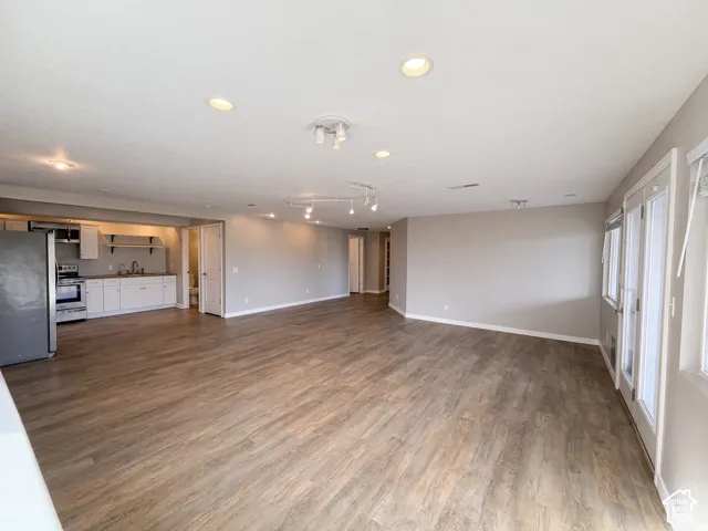 Open-concept interior featuring wood-finish flooring, recessed lighting, multi-track ceiling fixtures, and double glass doors