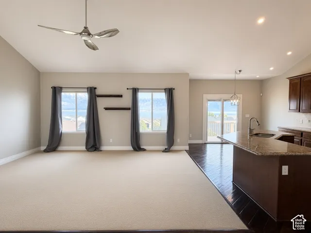Vaulted ceiling, kitchen island with stone countertop, dark wood-finish cabinetry, wood-finish flooring, and dual wall-mounted shelving units