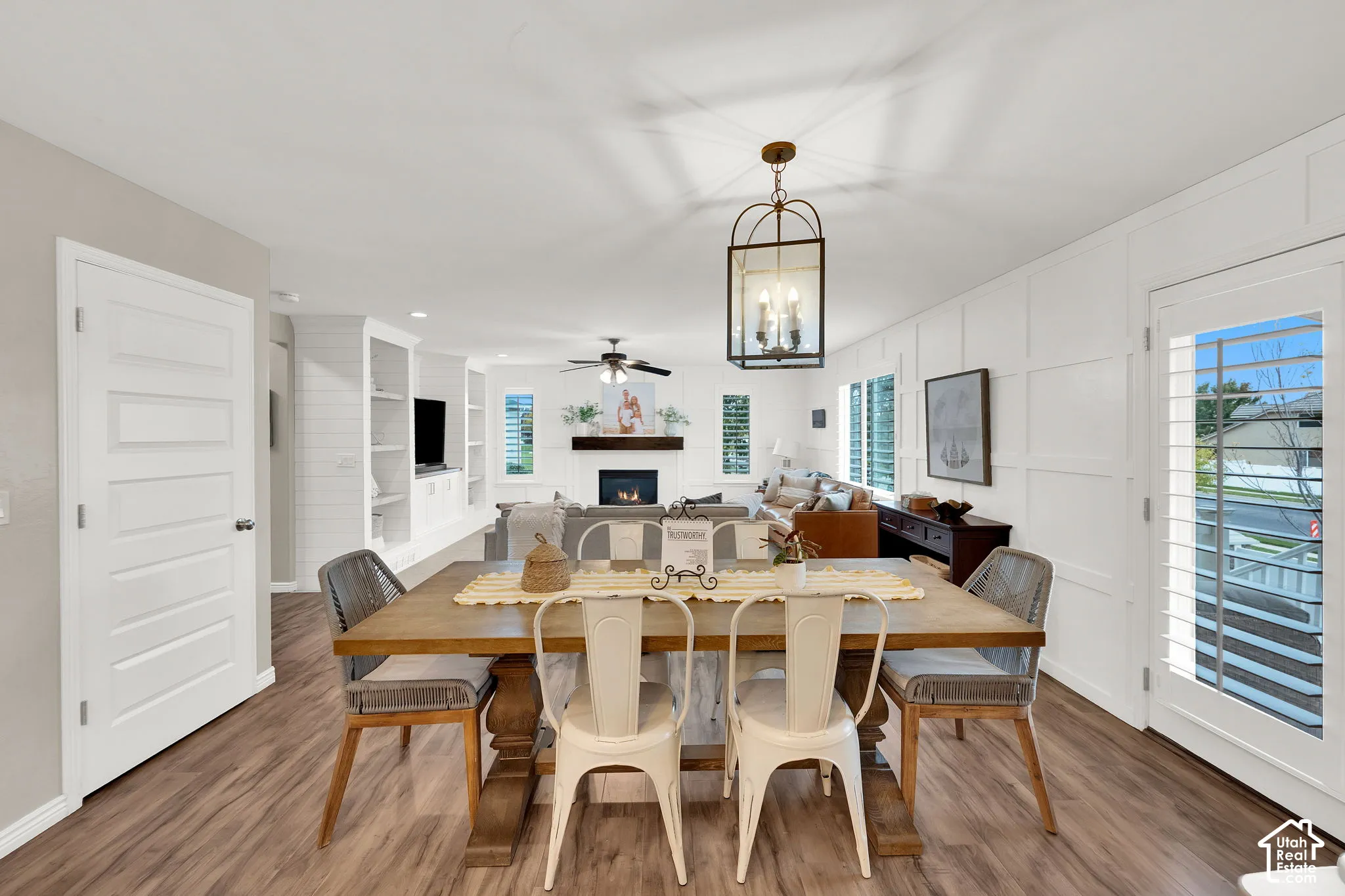 Dining area featuring wood-finish flooring, board and batten wall detailing, a classic lantern-style pendant light, and built-in shelving
