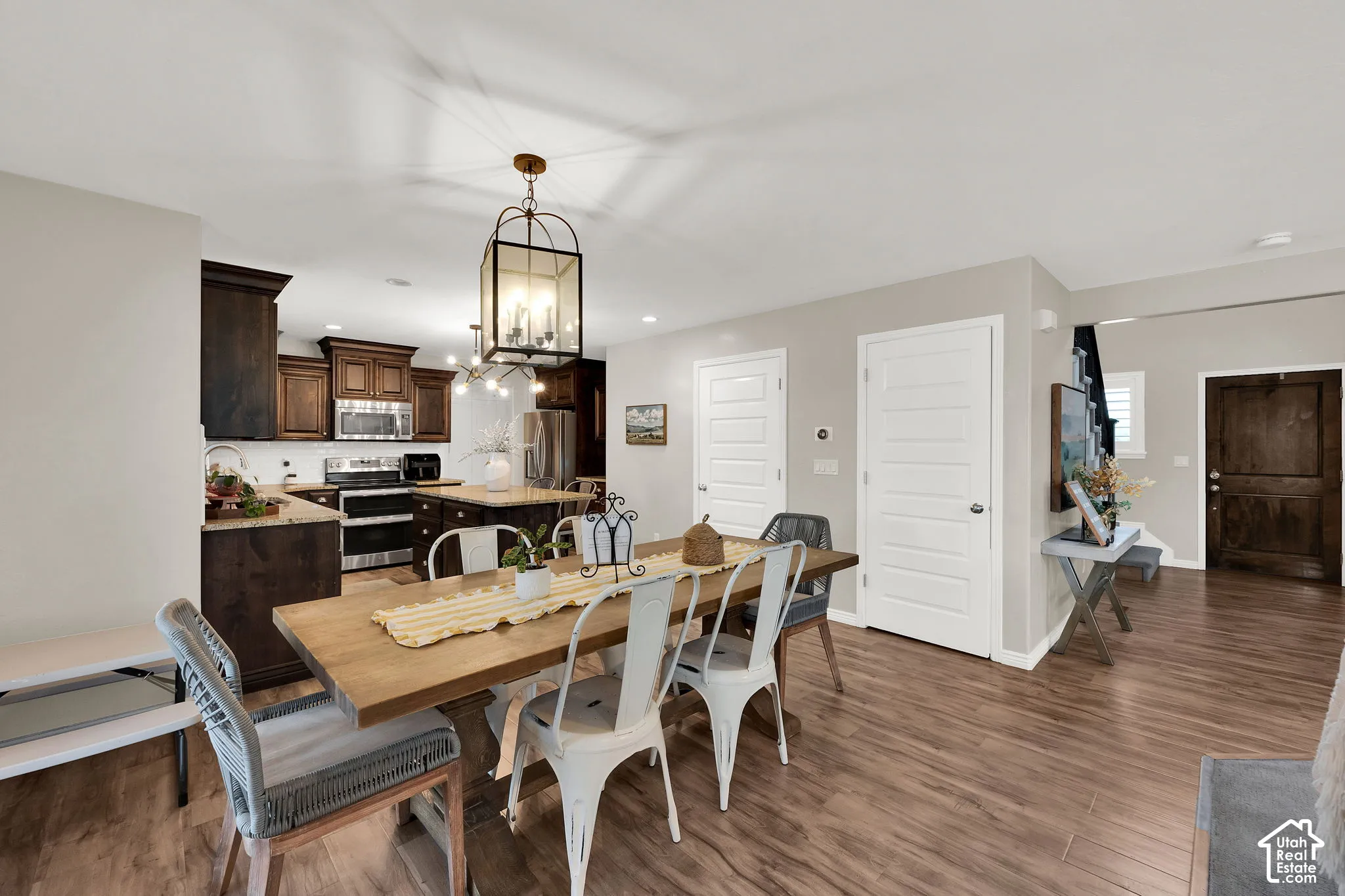 Kitchen featuring stained wood cabinetry, central island, stainless steel appliances, wood-finish flooring, and lantern-style pendant lighting