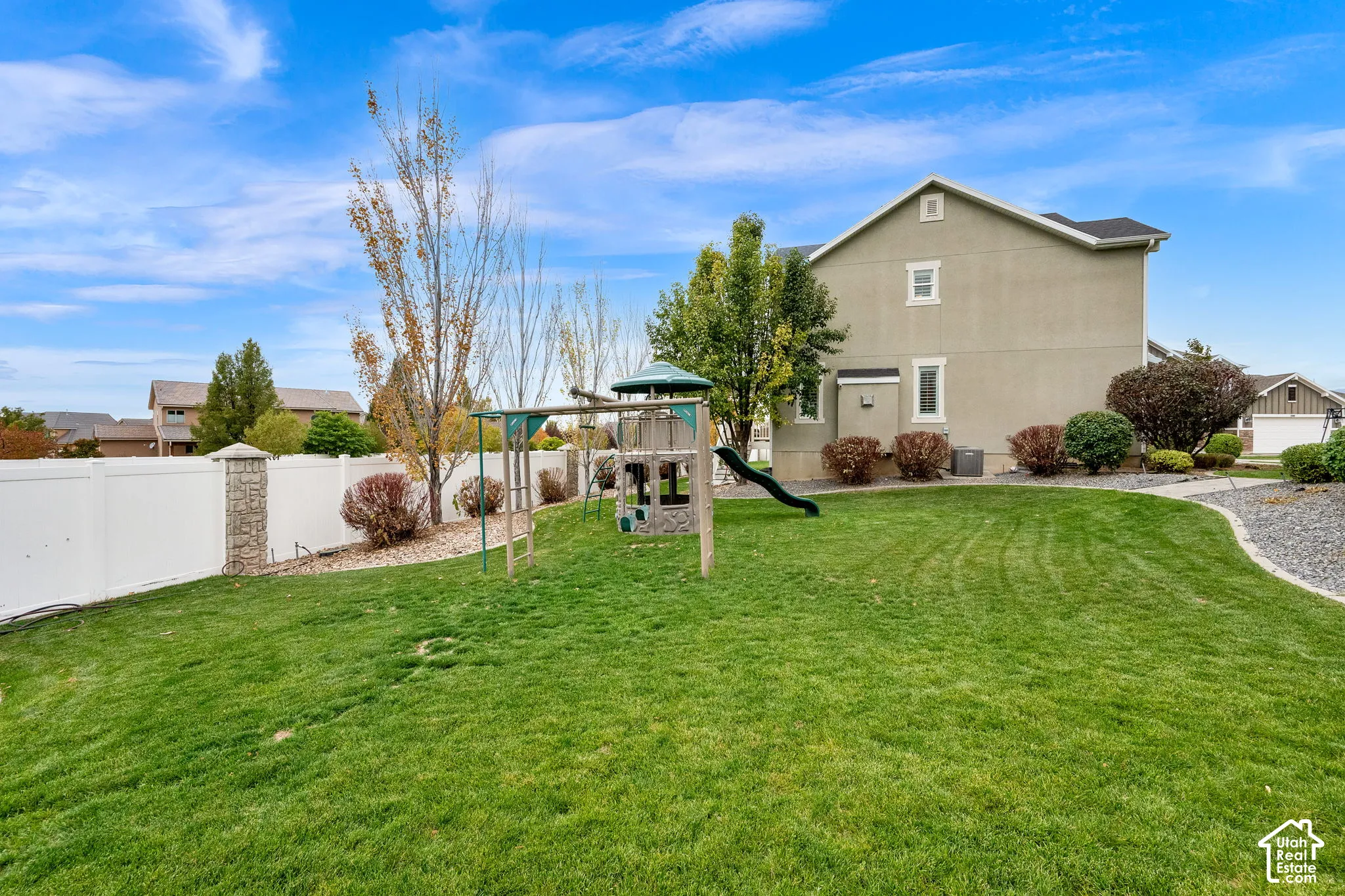 Backyard featuring a manicured lawn, white vinyl fencing with masonry columns, and mature landscaping