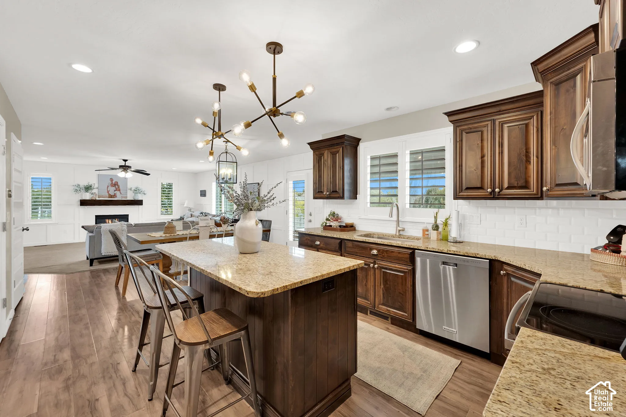 Kitchen featuring wood cabinetry, stone countertops, white tile backsplash, center island, and multi-light fixtures