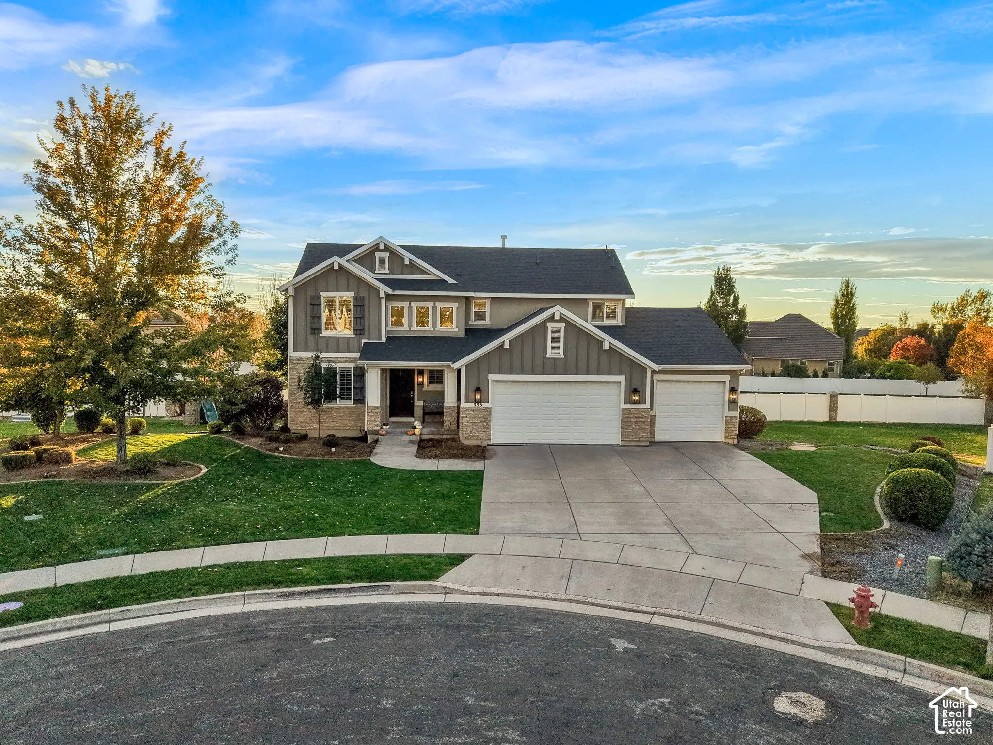Two-story residence featuring a board-and-batten siding exterior, stone veneer accents, multi-gabled roofline, three-car garage, and a concrete driveway