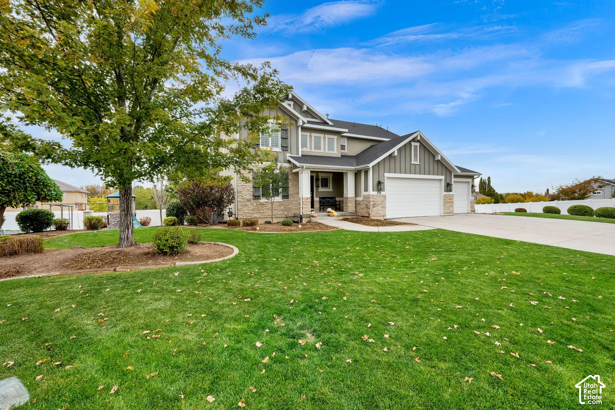 Multi-level exterior featuring a stone veneer facade, vertical board-and-batten siding, a covered entryway, and a three-car garage