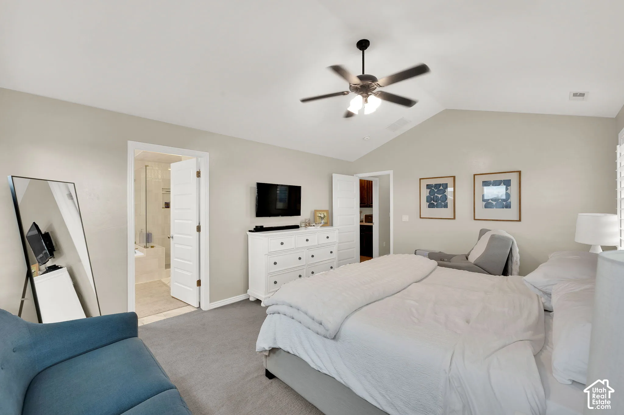 Vaulted ceilings, neutral wall tones, carpeted flooring, and a multi-blade ceiling fan with integrated lighting