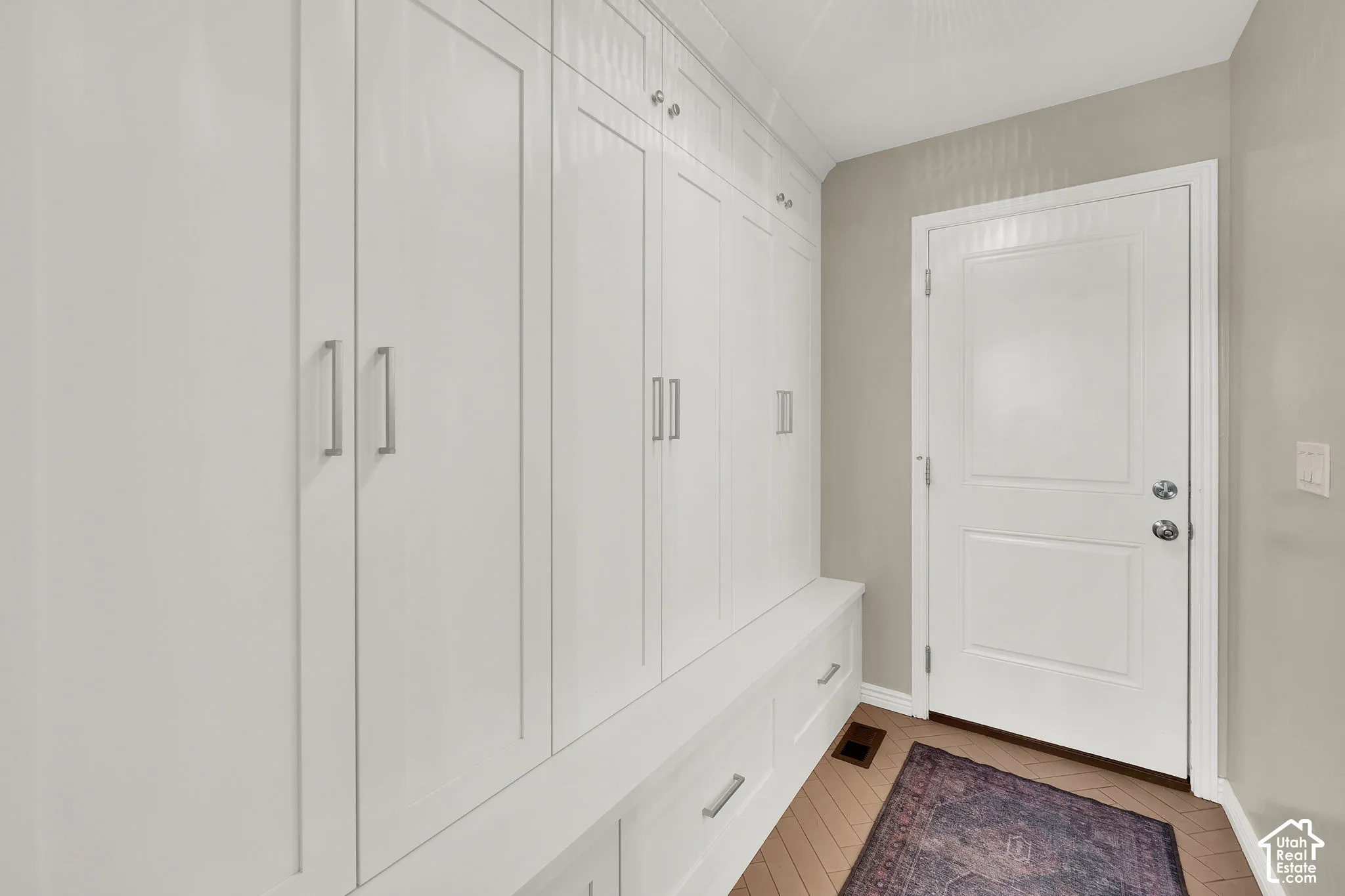 Floor-to-ceiling white shaker-style built-in cabinetry featuring brushed nickel hardware, integrated bench seating, and storage drawers