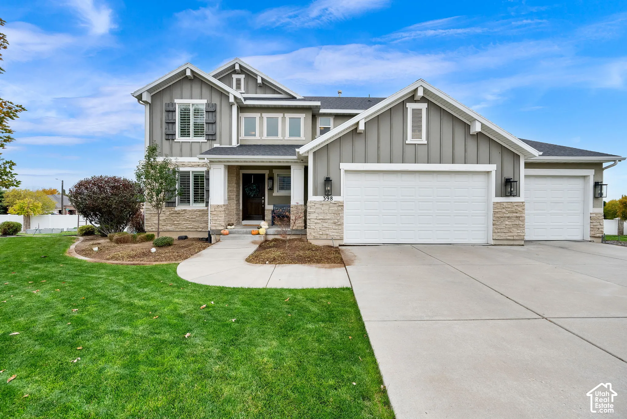 Multi-level exterior featuring vertical siding, stone veneer accents, a covered entryway, and an attached three-car garage