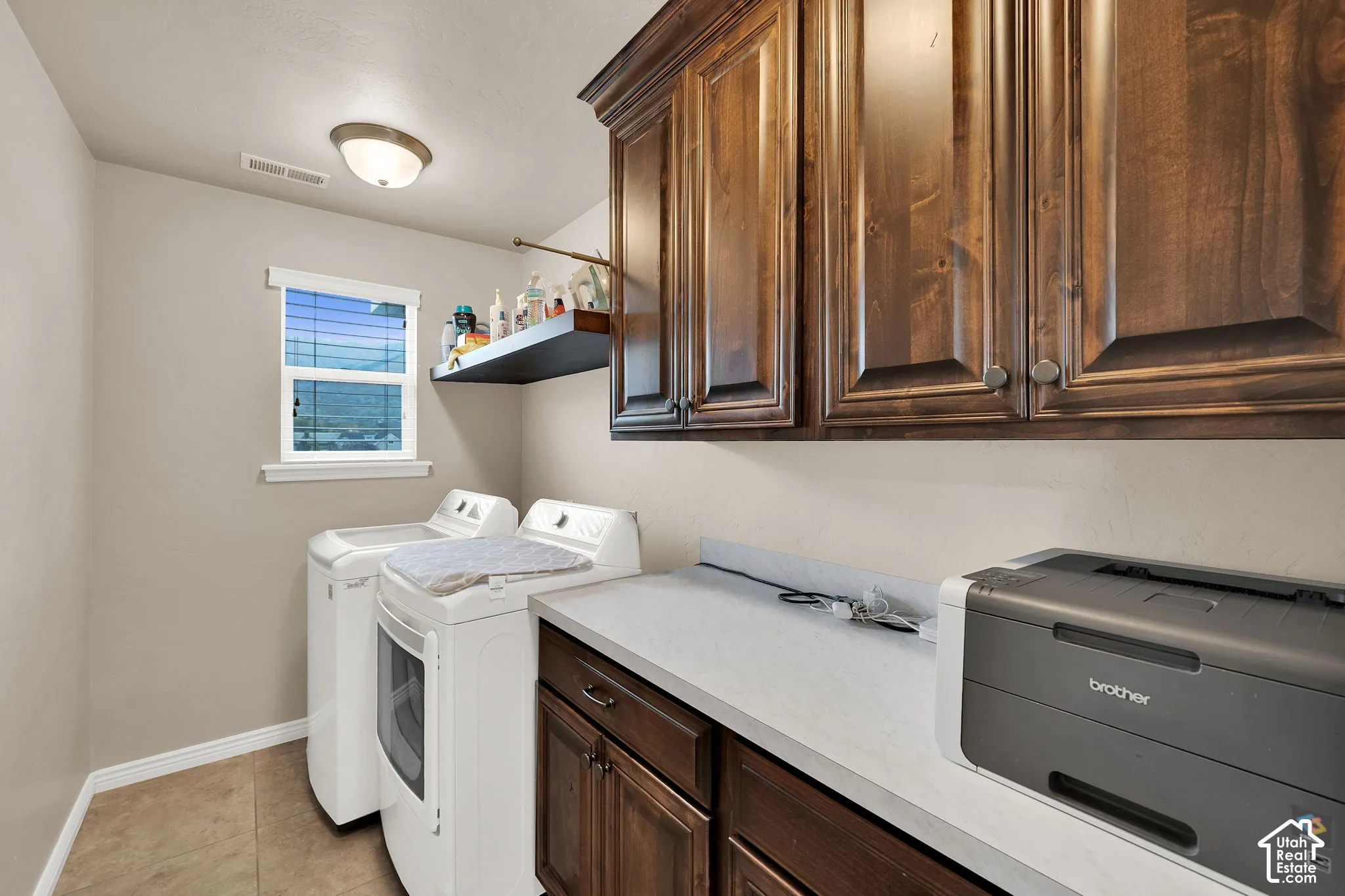 Stained wood cabinetry, solid-surface countertop, tile flooring, and wall-mounted shelving