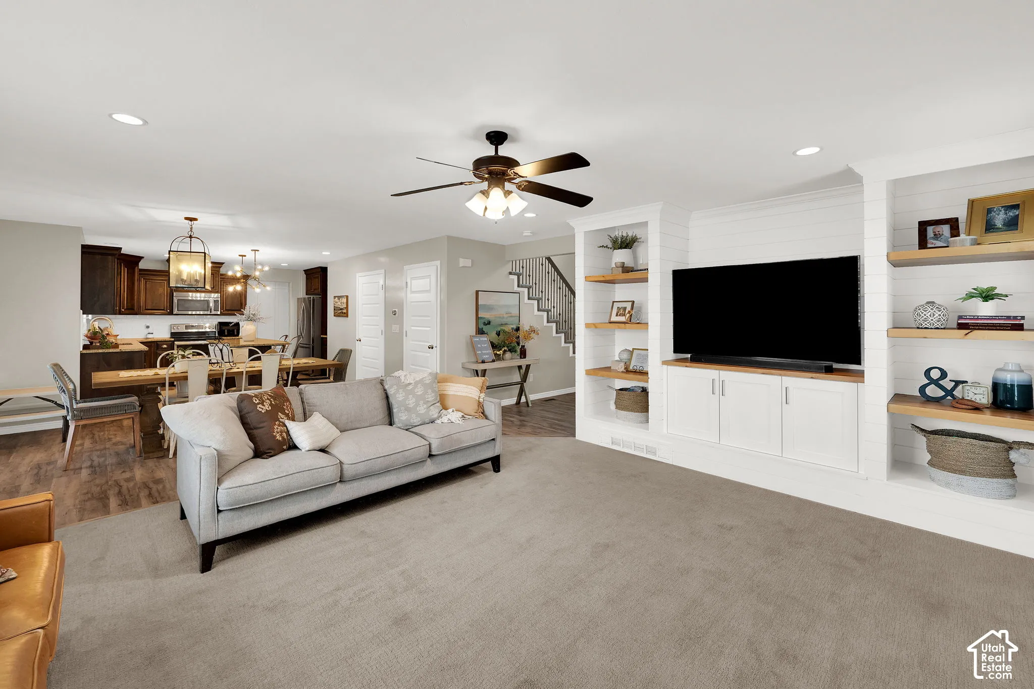 Custom built-in cabinetry featuring shiplap detailing and open wood shelving, recessed lighting, and a ceiling fan with integrated lighting
