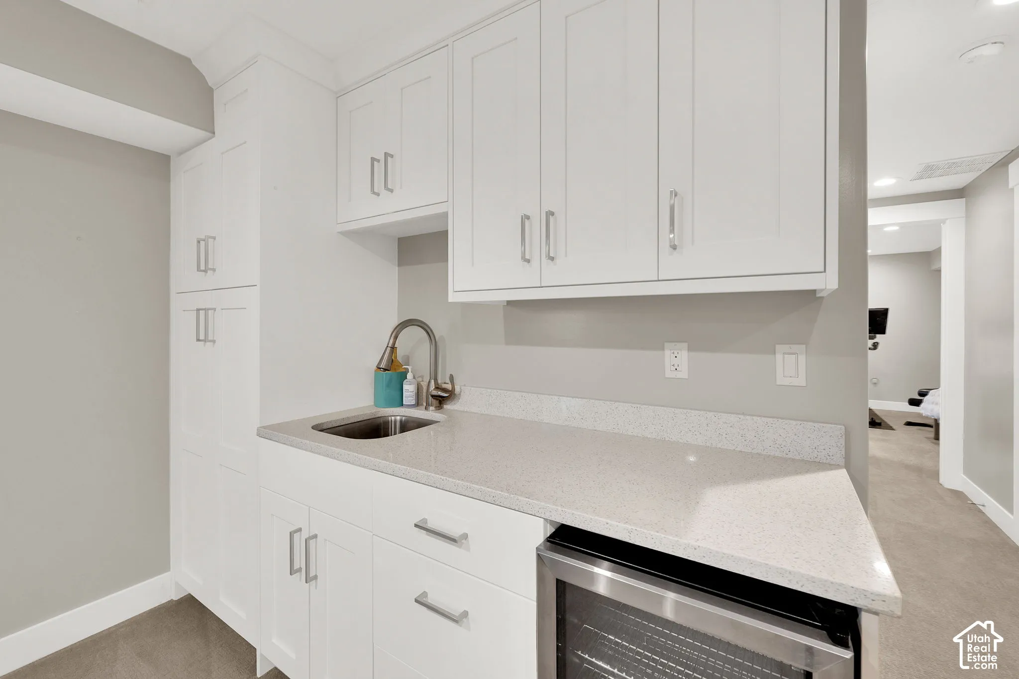 White shaker-style cabinetry, quartz countertop, stainless steel under-mount sink, high-arc faucet, and built-in under-counter beverage refrigerator