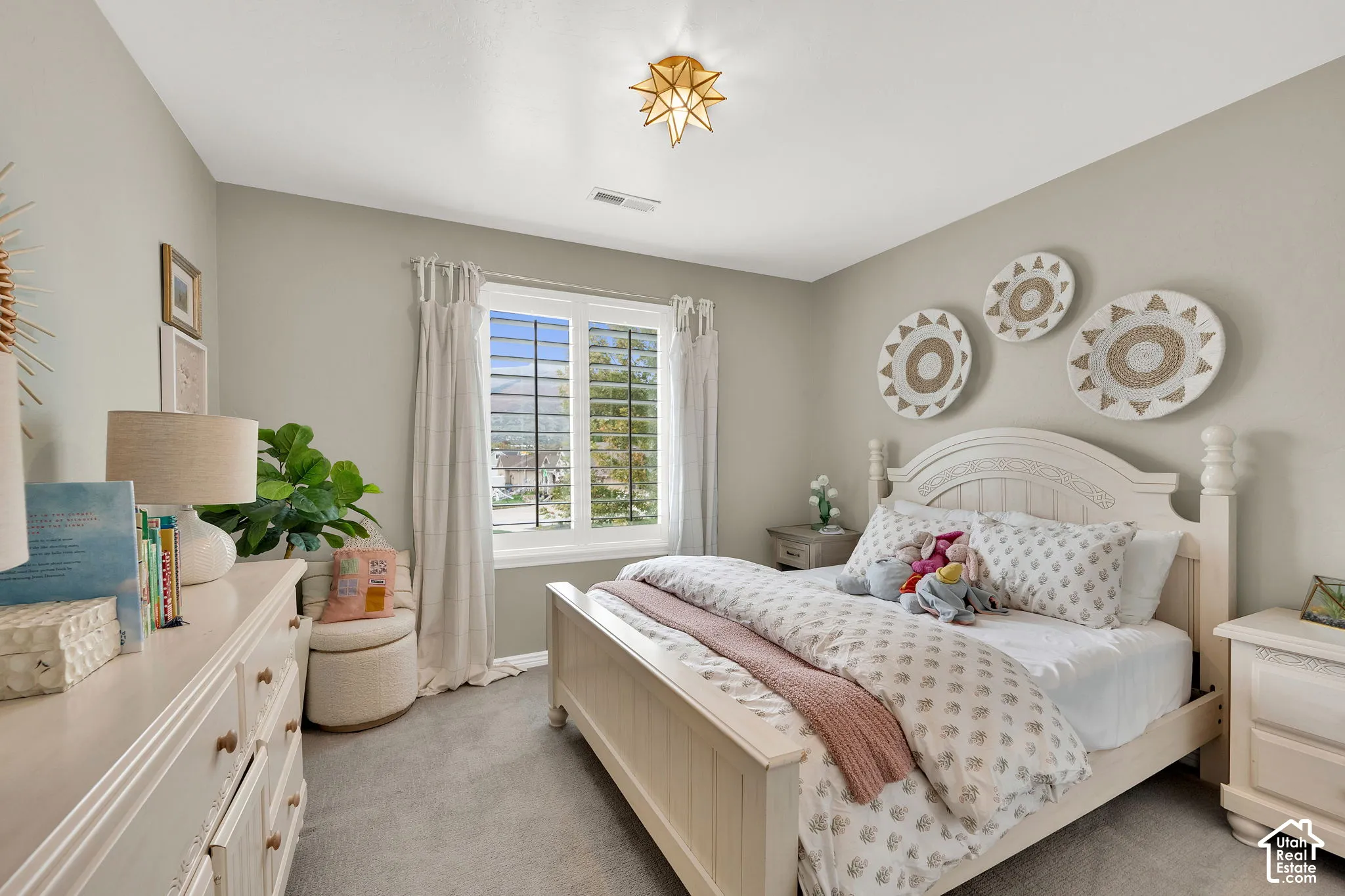 Neutral-toned walls, plush wall-to-wall carpeting, multi-pane window with custom interior shutters, and geometric starburst flush-mount ceiling fixture