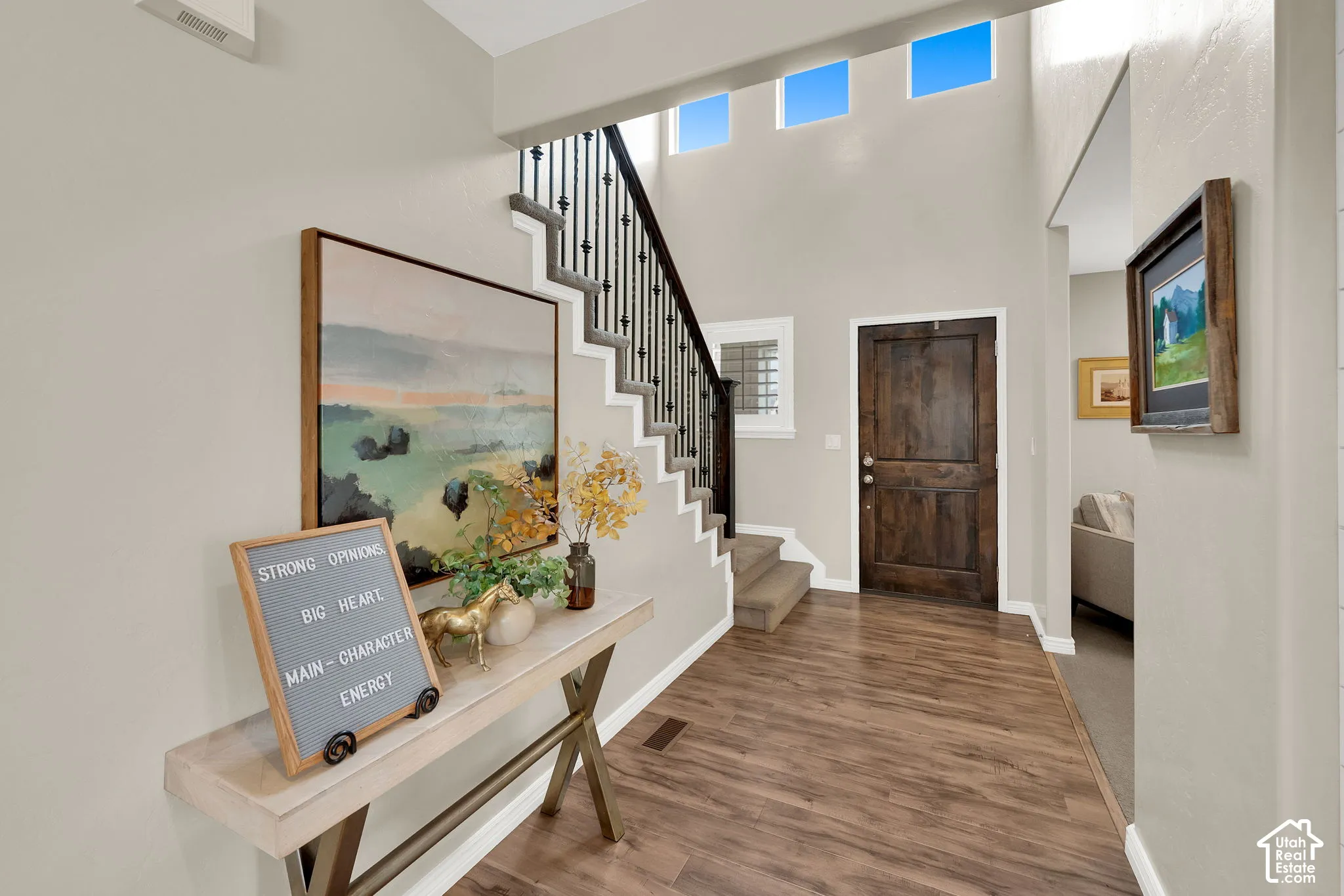 Grand foyer featuring a high ceiling with transom windows, wood-finish flooring, and a staircase with a wrought iron balustrade