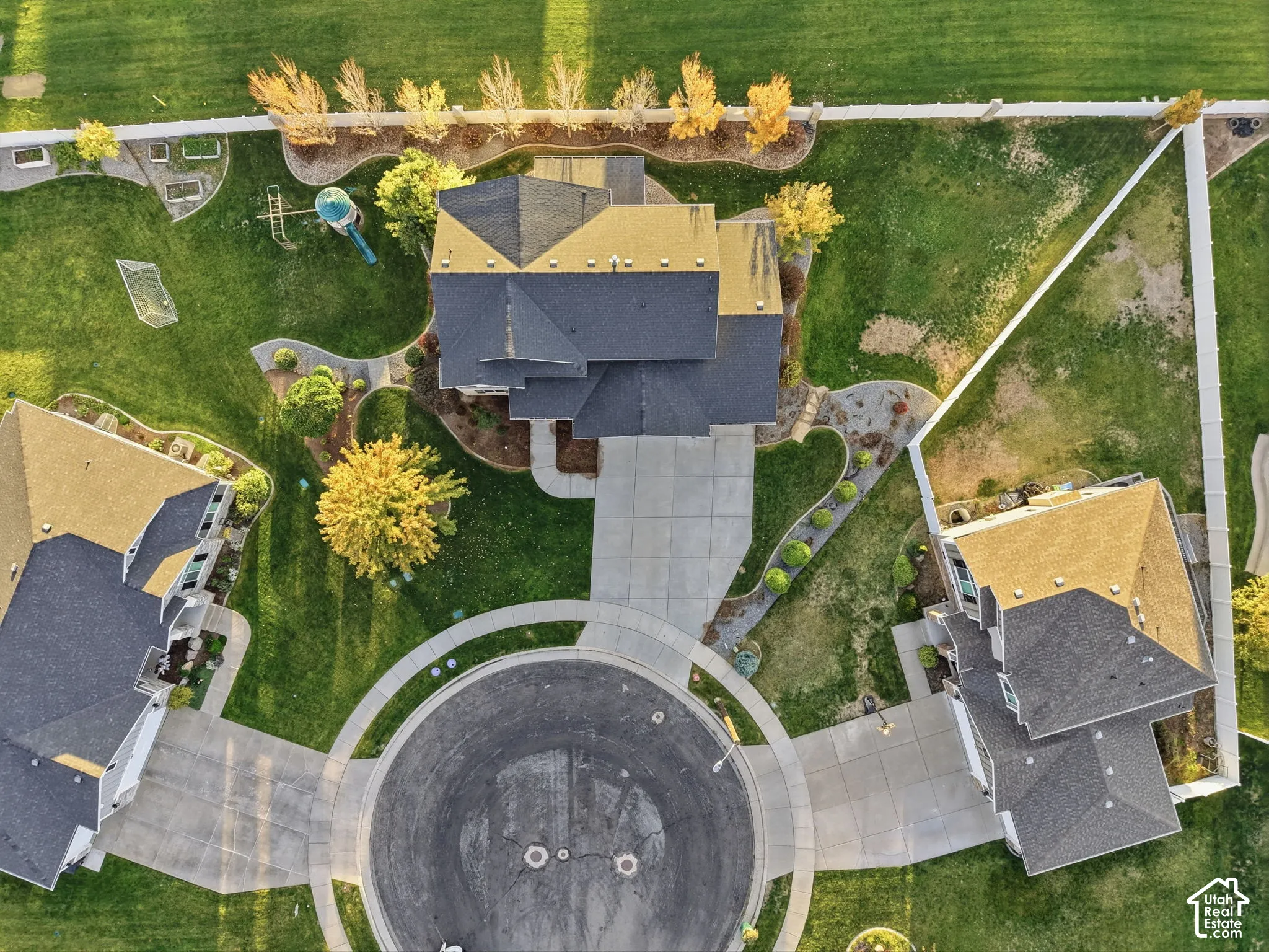 Expansive lot featuring a large lawn, mature trees, concrete driveway, and full perimeter fencing
