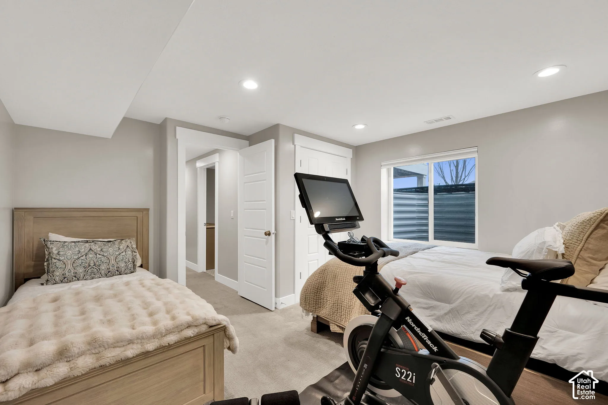 Neutral-toned interior featuring wall-to-wall carpeting, recessed ceiling lighting, a multi-panel door, and a dual-pane window