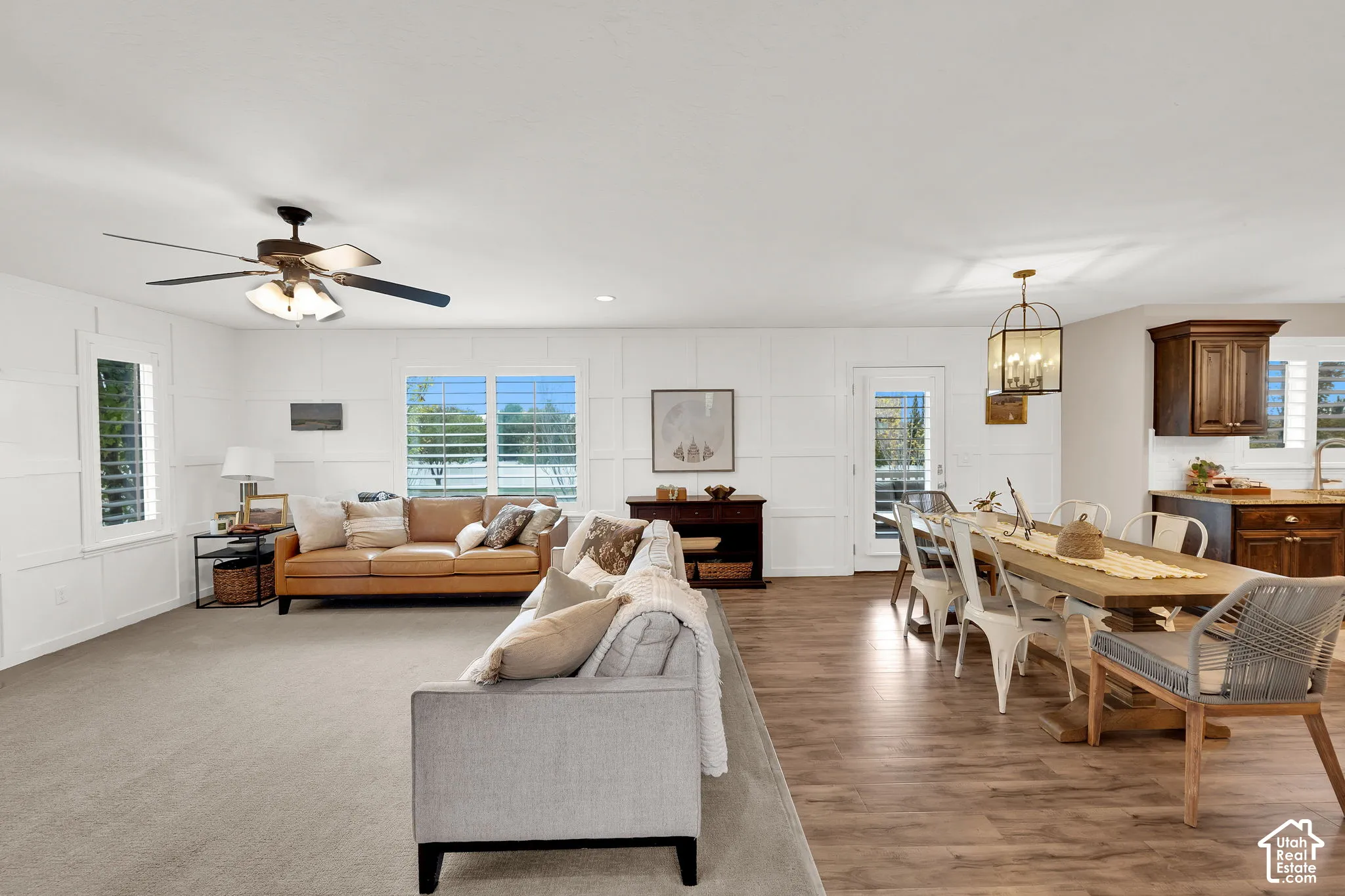 Interior space featuring crisp wall paneling, wood-finish flooring, a multi-blade ceiling fan, and lantern-style pendant lighting