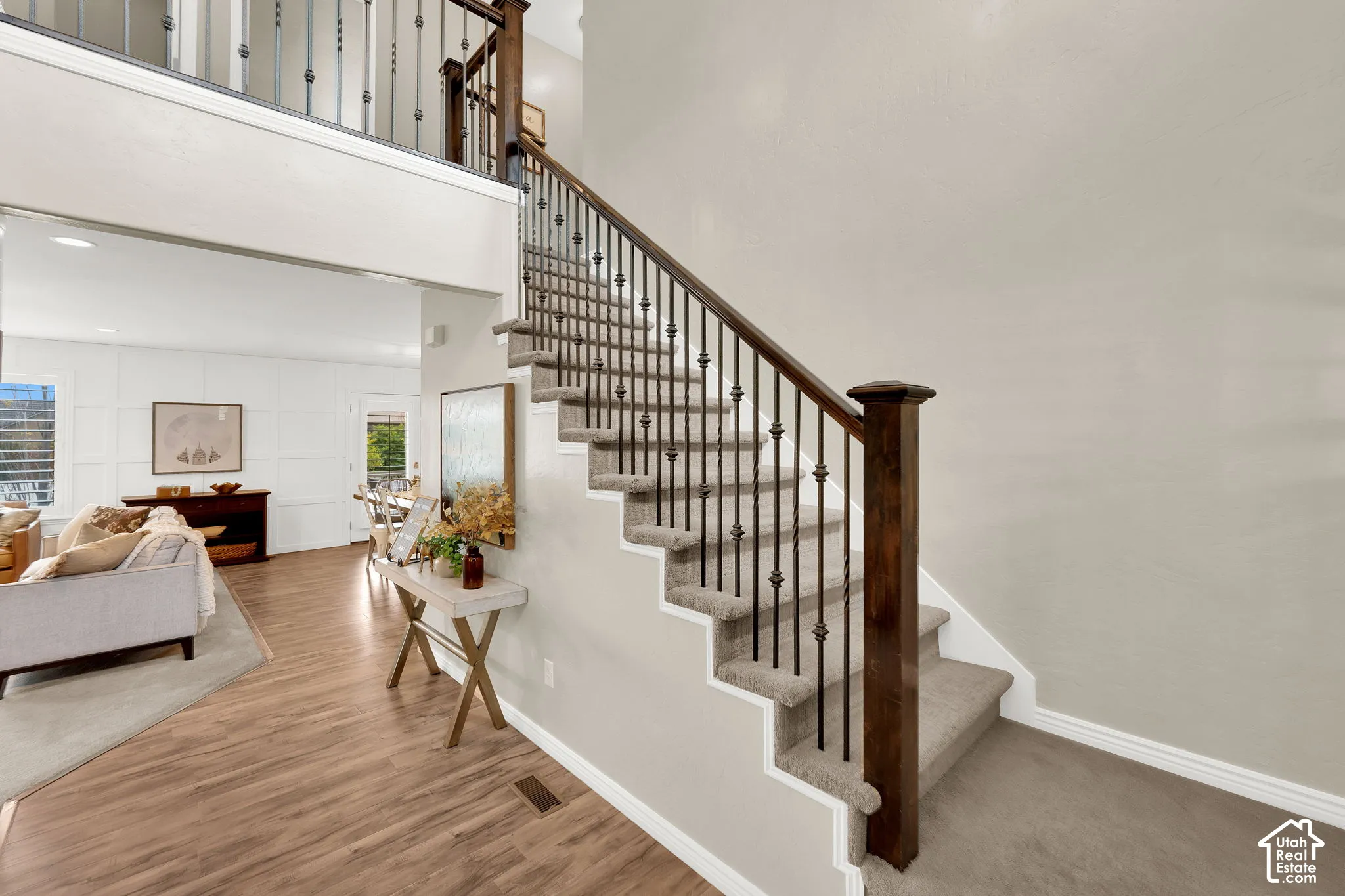 Staircase featuring dark wood handrails, decorative iron balusters, and carpeted treads
