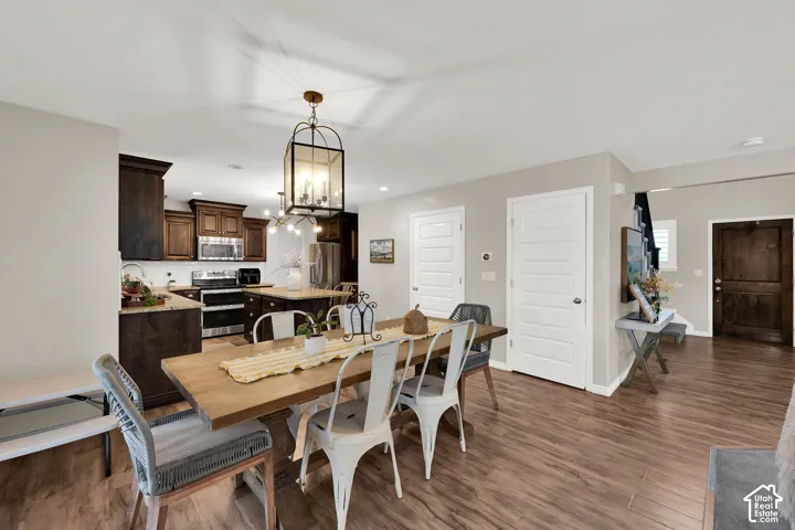 Kitchen featuring stained wood cabinetry, central island, stainless steel appliances, wood-finish flooring, and lantern-style pendant lighting