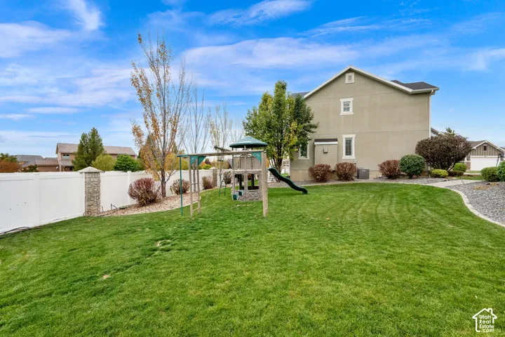 Backyard featuring a manicured lawn, white vinyl fencing with masonry columns, and mature landscaping