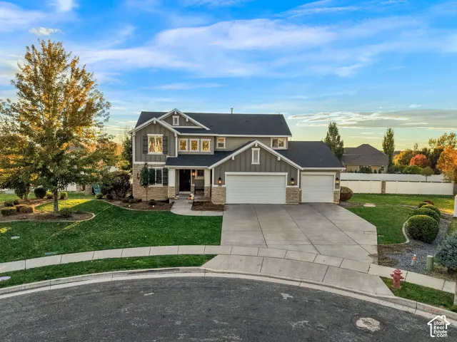 Two-story residence featuring a board-and-batten siding exterior, stone veneer accents, multi-gabled roofline, three-car garage, and a concrete driveway