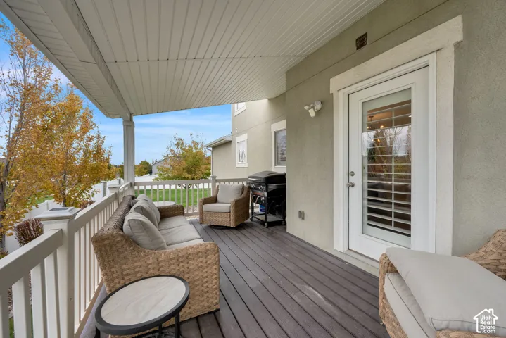 Covered deck featuring wood-finish flooring, a white spindle railing, and a full-light glass door