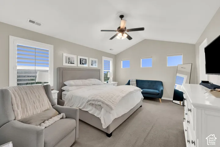 Vaulted ceilings, neutral wall tones, multi-pane windows with plantation-style shutters, high-placed accent windows, and a central ceiling fan with integrated lighting
