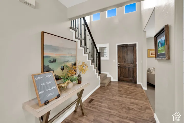 Grand foyer featuring a high ceiling with transom windows, wood-finish flooring, and a staircase with a wrought iron balustrade