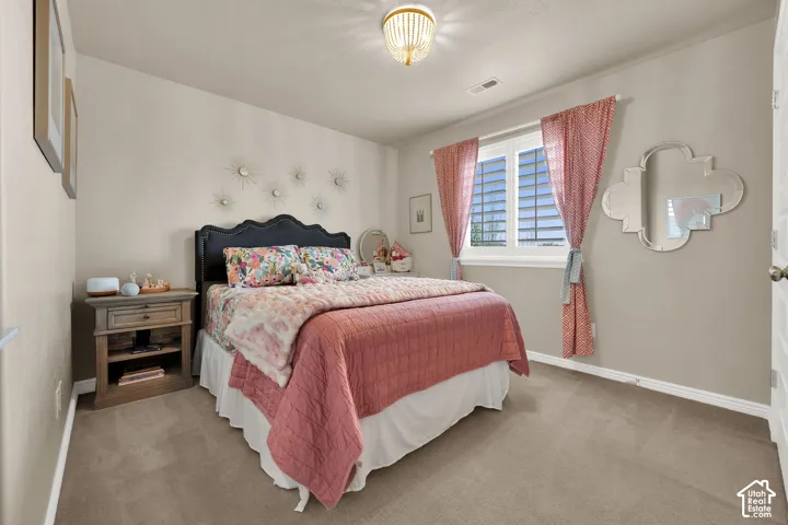Bedroom featuring neutral wall paint, wall-to-wall carpeting, window shutters, and a decorative semi-flush mount ceiling fixture