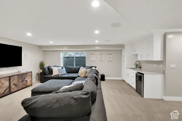Recessed ceiling lighting, wet bar featuring white cabinetry, quartz-finish countertop, stainless steel under-counter beverage refrigerator, and neutral carpeting