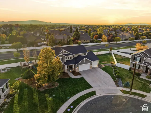 Multi-level residence featuring a multi-gabled roofline, stone and siding exterior, attached three-car garage, concrete driveway, and landscaped front yard