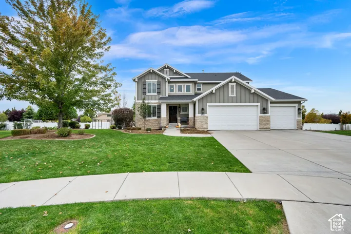 Two-story exterior featuring board-and-batten siding, stone veneer accents, a three-car garage, and a concrete driveway