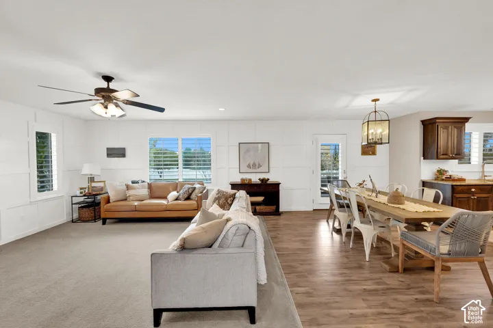 Interior space featuring crisp wall paneling, wood-finish flooring, a multi-blade ceiling fan, and lantern-style pendant lighting