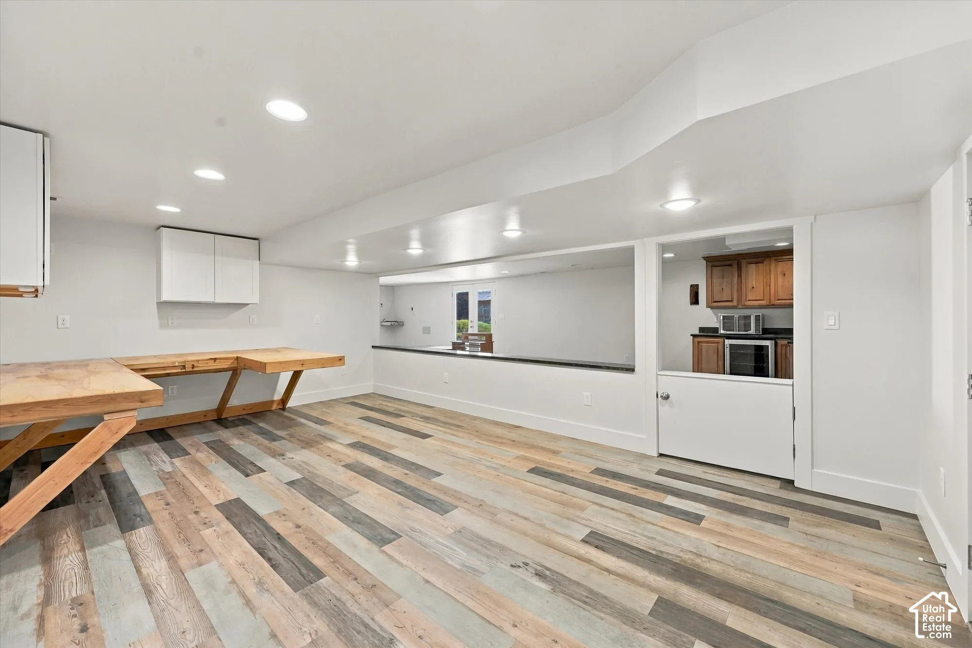 Multi-tone wood-finish flooring, built-in wooden workspace, recessed ceiling lighting, pass-through opening with stone surface, and Dutch door