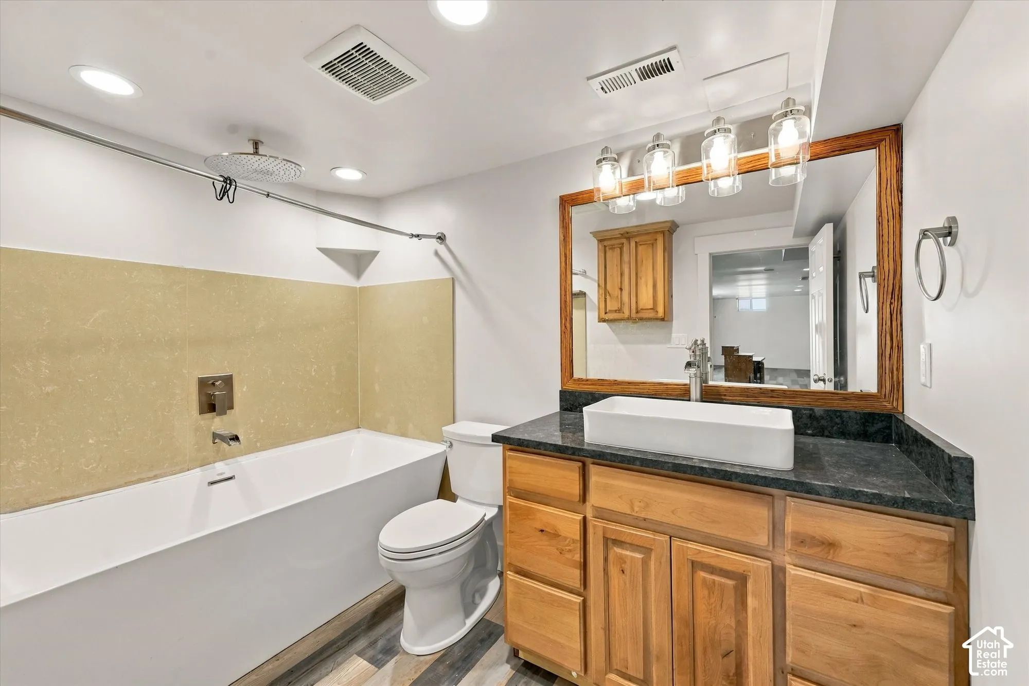 Bathroom featuring a vanity with wood cabinetry, a dark stone countertop, and a rectangular vessel sink
