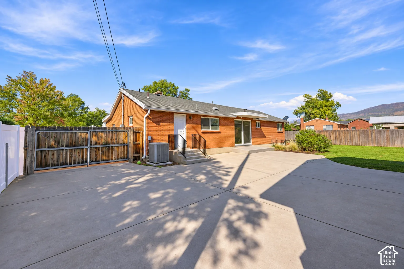 Brick exterior featuring a concrete patio, wood-finish gated access, and a fenced yard