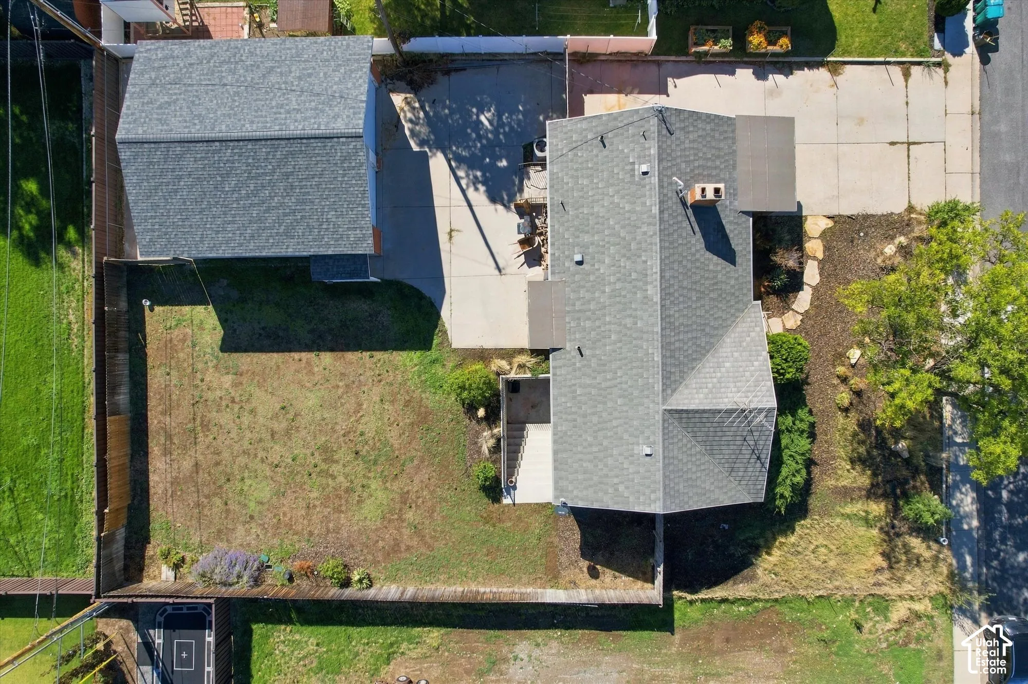 Aerial perspective featuring a detached garage, concrete driveway, fenced yard, and shingled roof