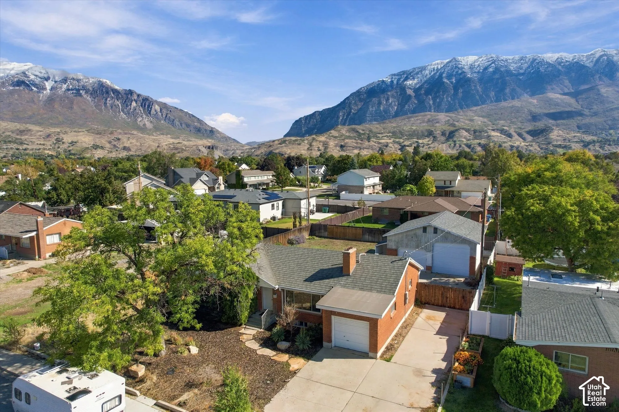 Single-story brick residence featuring a concrete driveway, attached garage, detached secondary garage, and prominent mountain backdrop