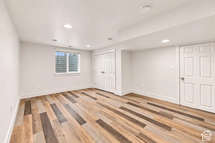 Room featuring wood-finish flooring, recessed lighting, white six-panel interior doors, and a single-pane window with a light well