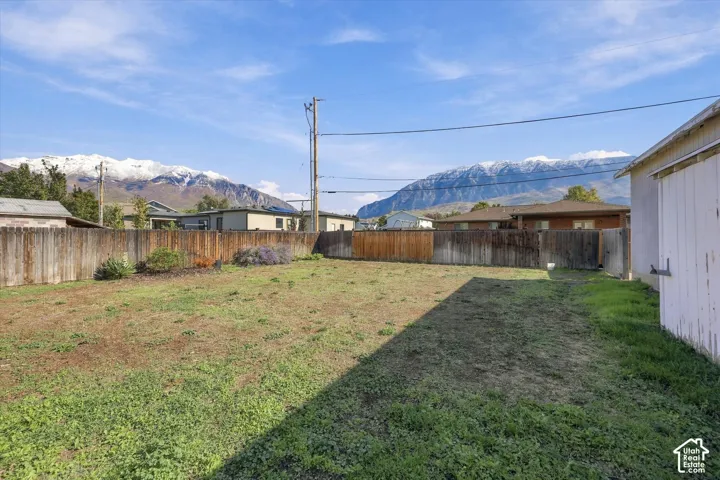 Expansive backyard featuring wood fencing, mature greenery, and mountain topography
