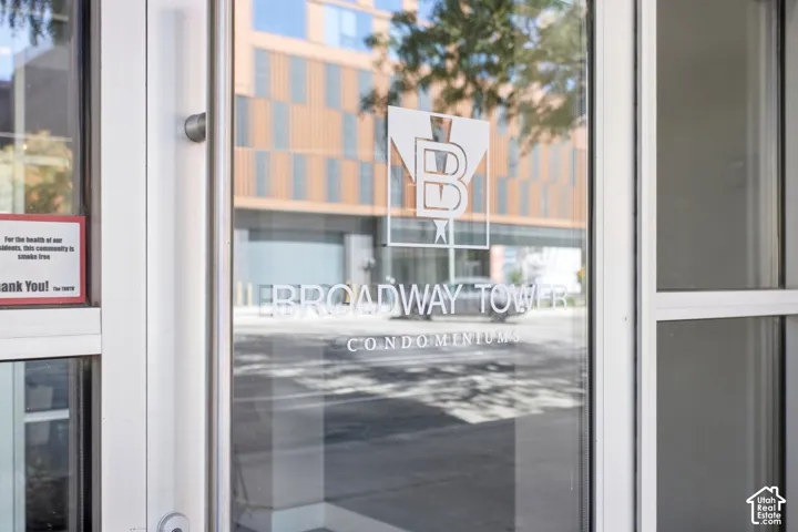 Commercial-grade glass entry door featuring a brushed metal pull handle and etched building signage